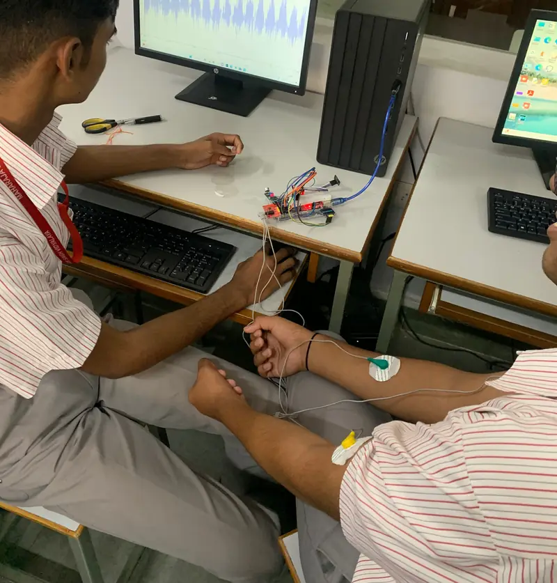 Prototype test in a computer lab: electrodes on a forearm, wired to the board, ECG trace on the monitor